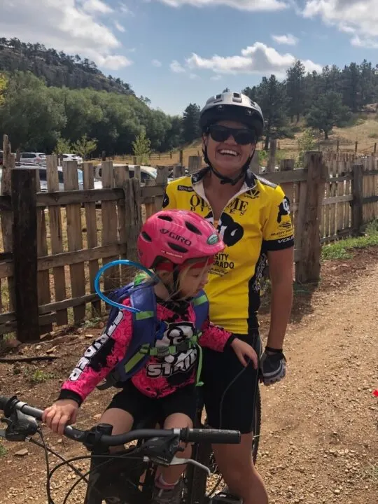 Little girl riding on mom's bike during trail ride. 