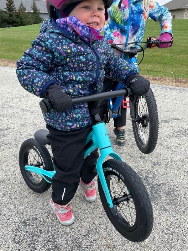 Girl on Hornit Airo balance bike pops a wheelie..