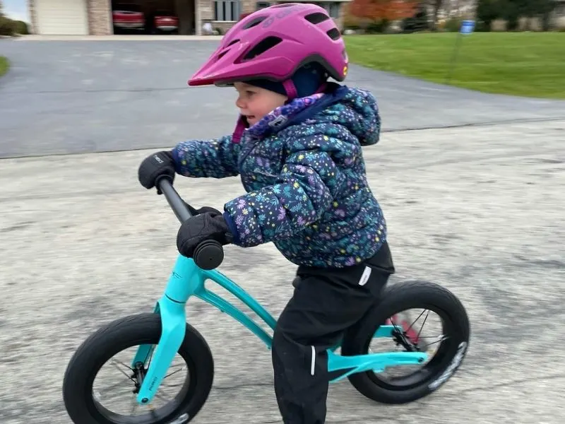 Girl riding Hornit Airo balance bike on road.