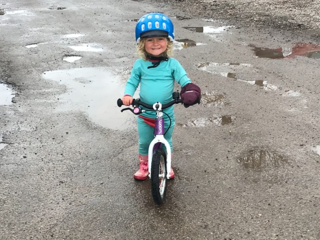 A toddler gives a huge smile while riding her Woom bike!