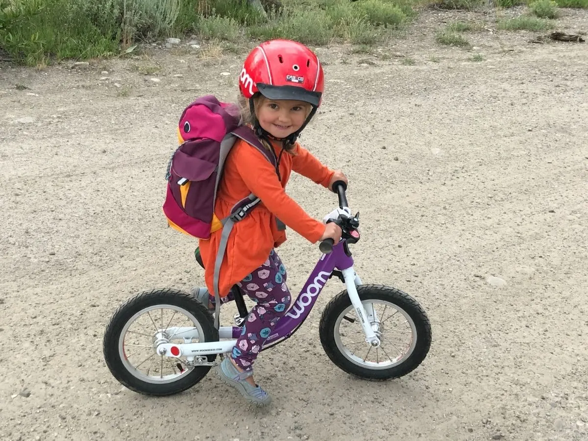 This toddler smiles brightly as she rides her Woom 1.