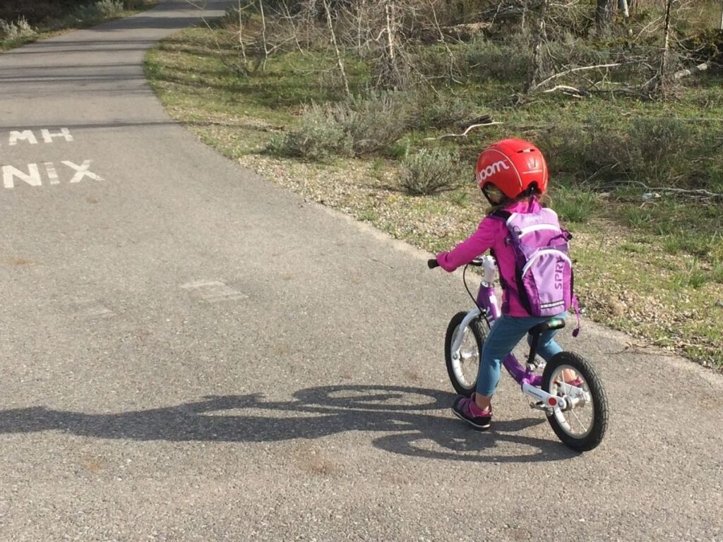 Child rides Woom 1 on street.