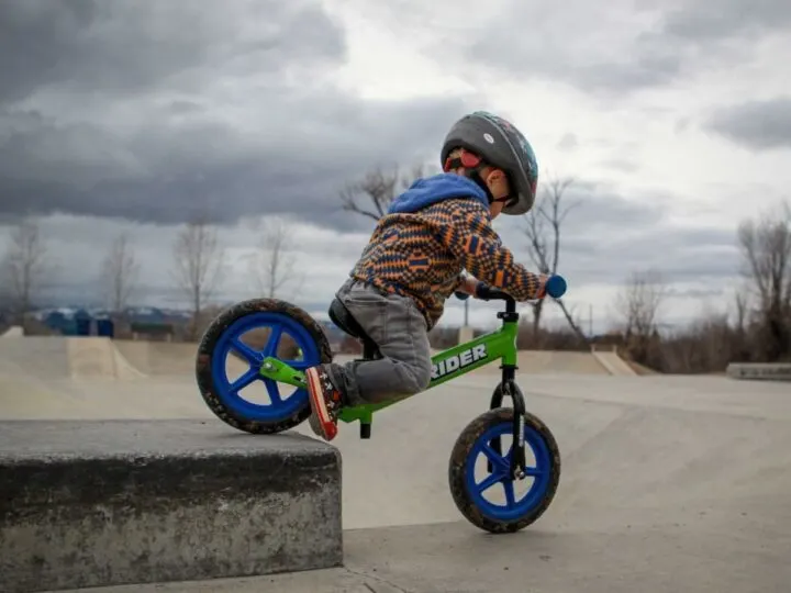 Little boy going off a drop at the bike park on a balance bike.
