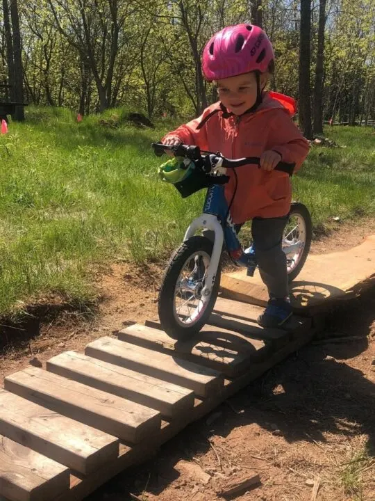 Kid riding a feature at bike park on balance bike.