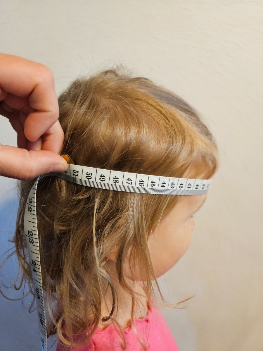 Little girl having his head circumference measured