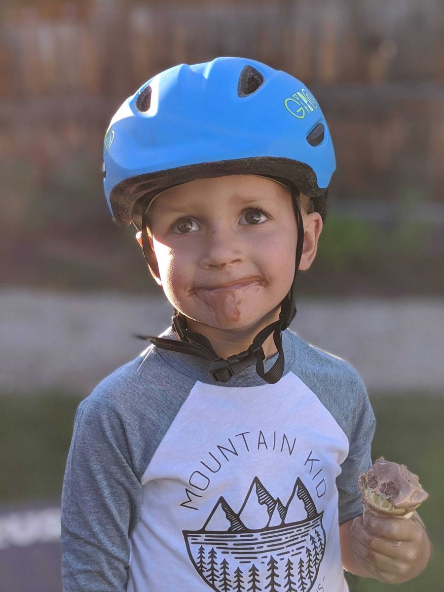 Little boy holding an ice cream cone wearing a Giro scamp helmet