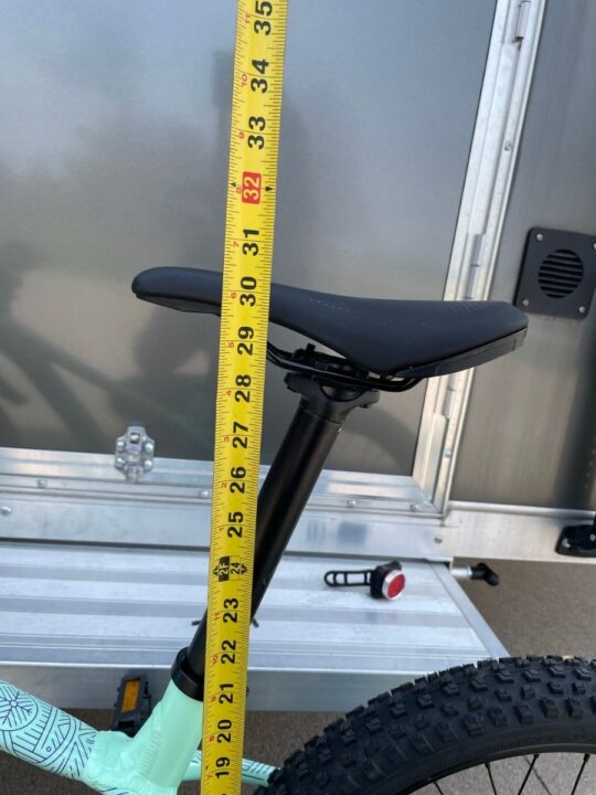 Tape measure next to bike seat showing height of seat.
