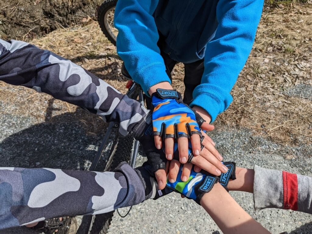 photo of several hands stacked on top of each other wearing bike gloves