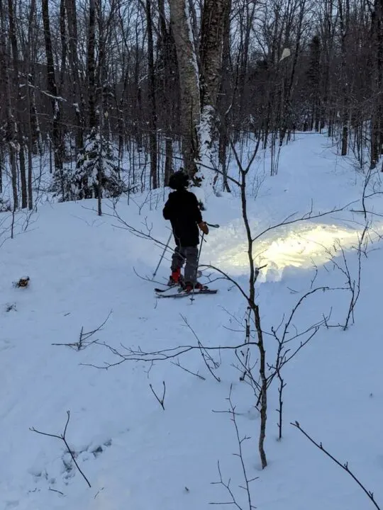 A boy illuminates his path with a helmet-compatible light while backcountry touring.