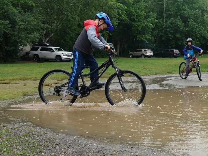 A boy rides his bike through a muddy puddle. Bike lights for kids.