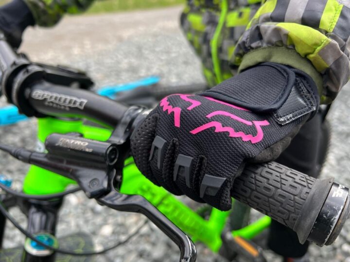 close-up photo of child's hands gripping handlebars while wearing Fox Dirtpaw bike gloves