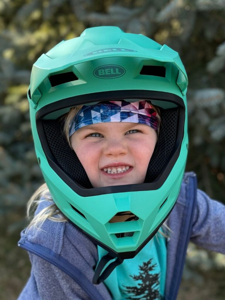 A young girl wears the Bell Sanction 2 helmet in teal.