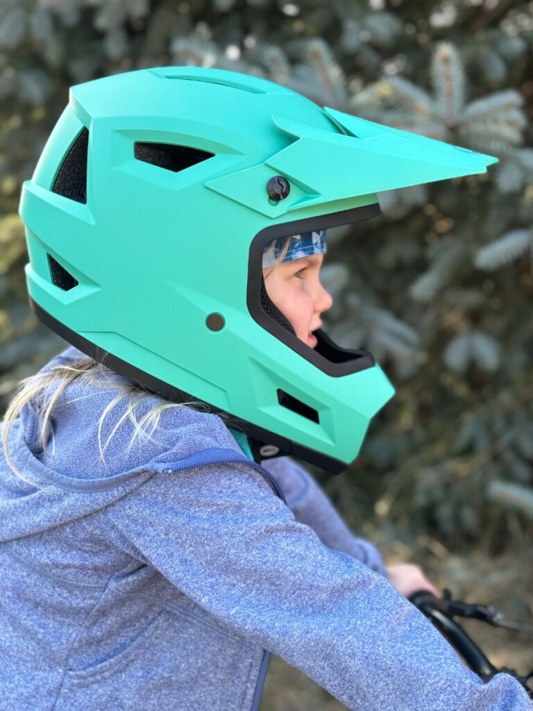 A young girl wears the Bell Sanction 2 helmet in teal.