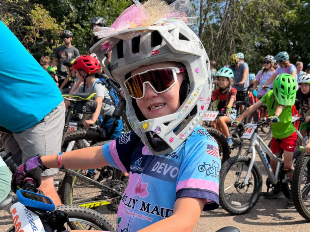FullFaceIXSTriggerO2S A young girl wears a grey full face bike helmet with some tulle on the top and gems on the side.