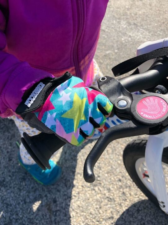 photo of a child's hand wearing a bike glove and holding onto bike handlebars
