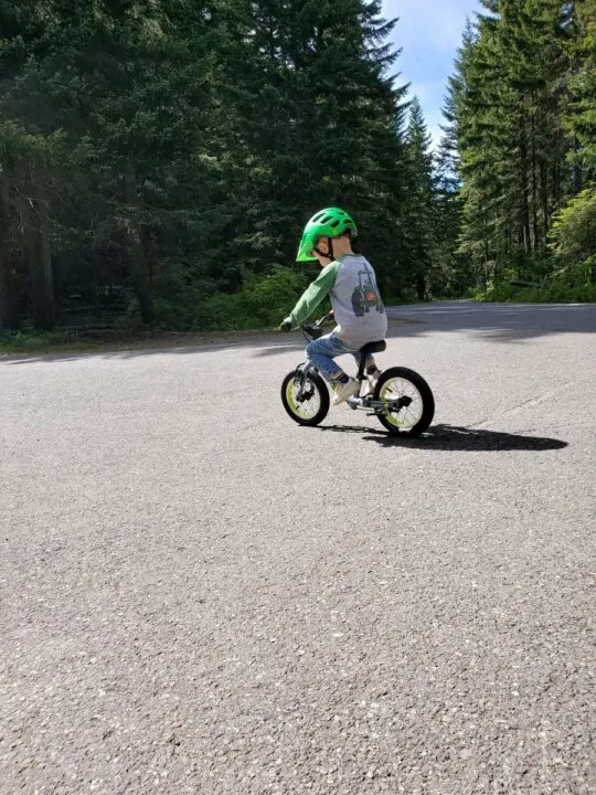 little boy balancing his feet on the balance bike