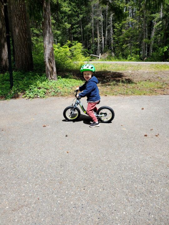 little boy sticking his tongue out riding a balance bike