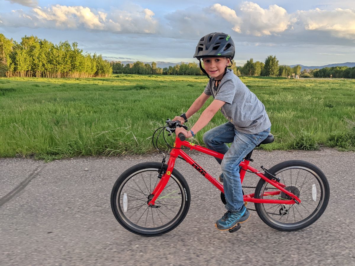A boy smiles while riding a red bike