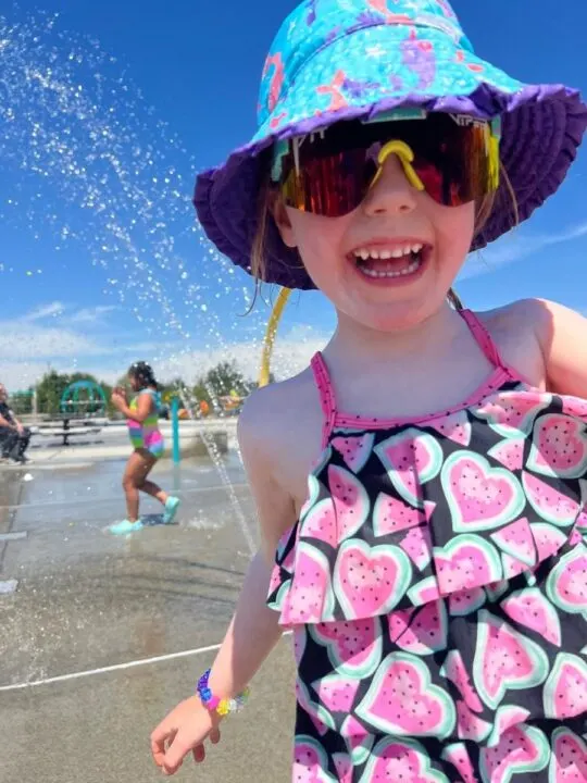 Photo of a child in a swimsuit playing sprinklers at the Cordata Park splash pad