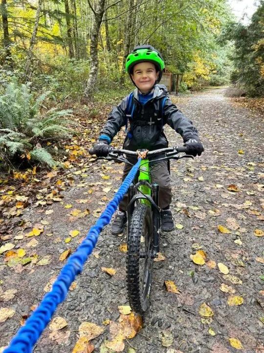 photo of a child being towed uphill on his mountain bike