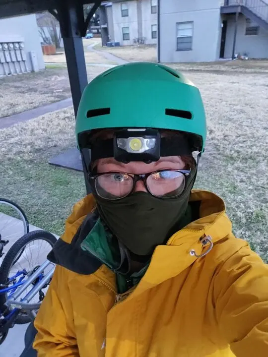 A selfie of a woman wearing glasses and a teal helmet.