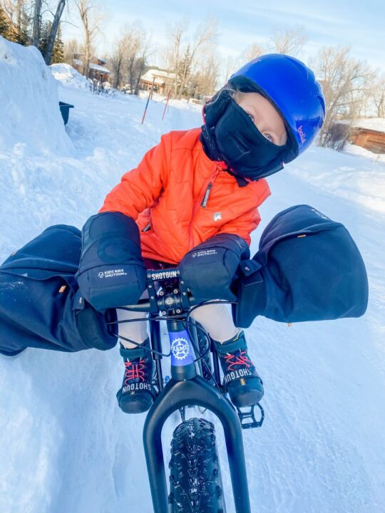 Young child all bundled up on her shotgun Pro seat on a bike in winter with Pogies handle bar covers