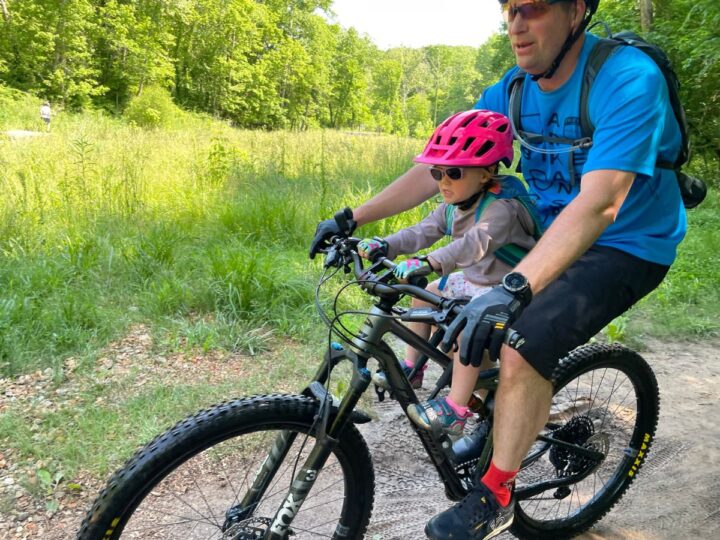 Dad and daughter mountain biking together using the Kids Ride Shotgun Pro seat.