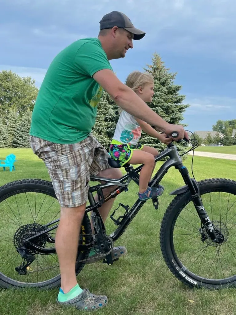 Dad and daughter demonstrating body position on a mountain bike with the original shotgun seat.