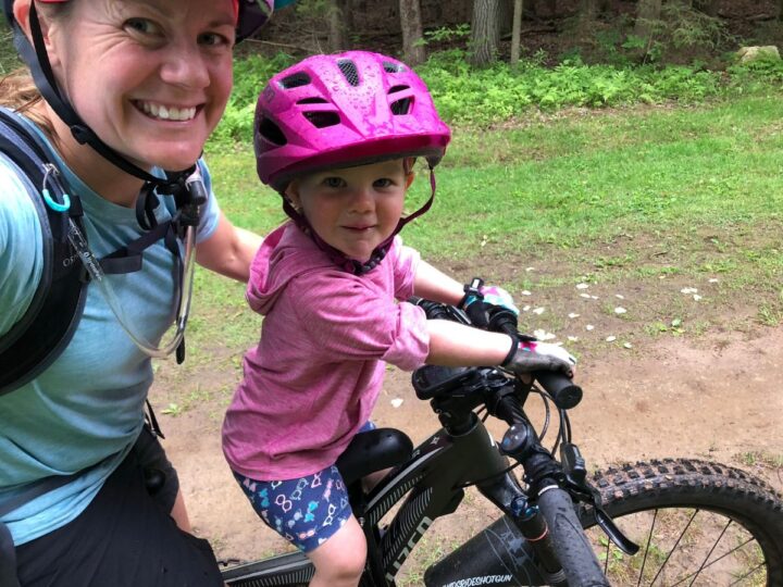 Mom and daughter mountain biking together using a Kids Ride Shotgun seat.