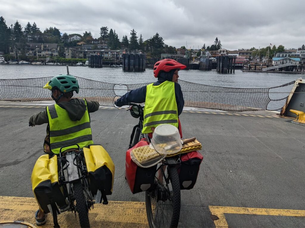 Two boys prepare to ride off a ferry boat on their bikes.