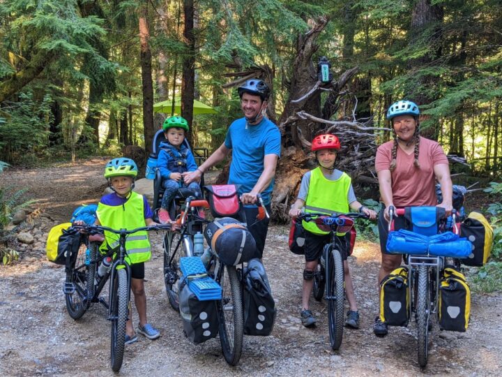 A family of five lines up with their loaded touring bikes amidst the trees