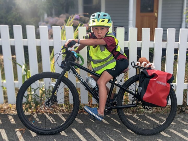 A boy poses with his black bike.