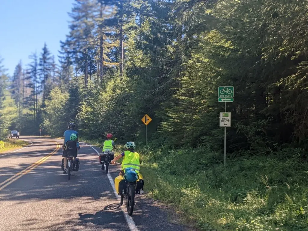 A family of cyclists ride along a signed bike route road.