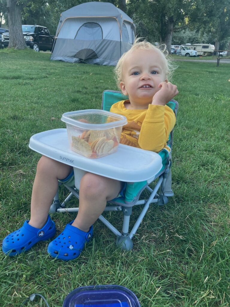 Baby eating snacks in his camp chair.