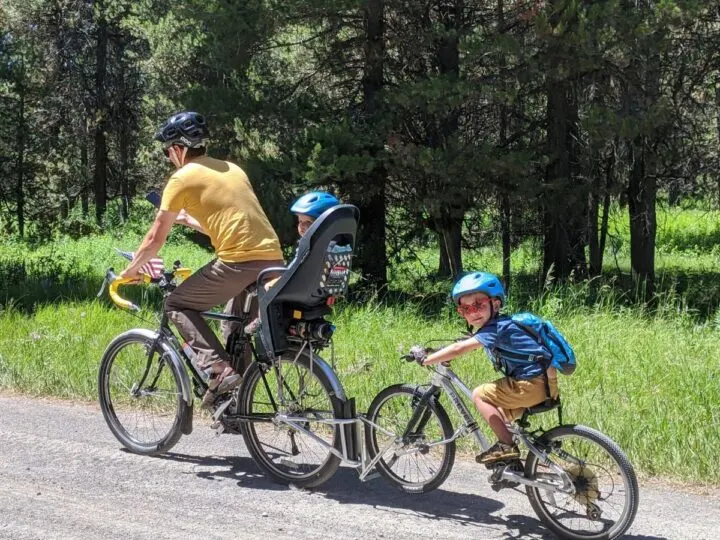 A father and son ride bikes coupled together by a follow me tandem.