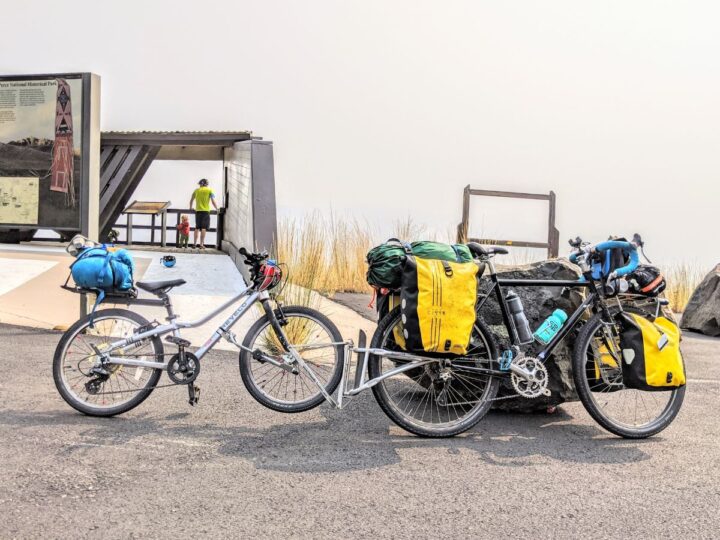 A kids and adult bike are coupled together using the follow me tandem, loaded for a bike tour.