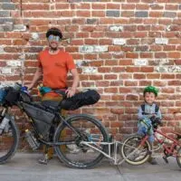 dad and son pose with bikes coupled by a follow me tandem.