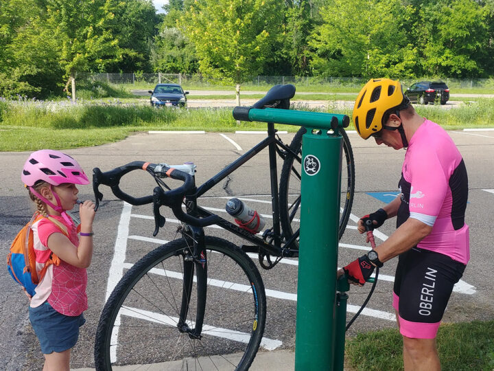 Father and daughter at a bike repair stand with a bike between them. 