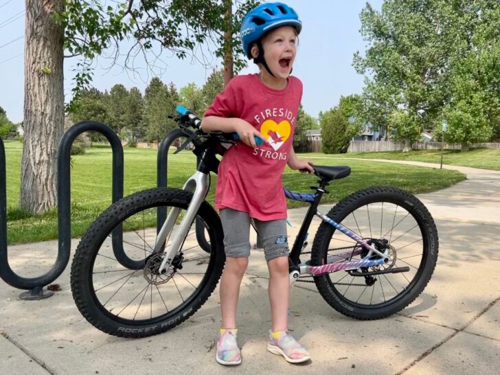 Biking to school. Kid excited in front of her bike at school bike parking lot.