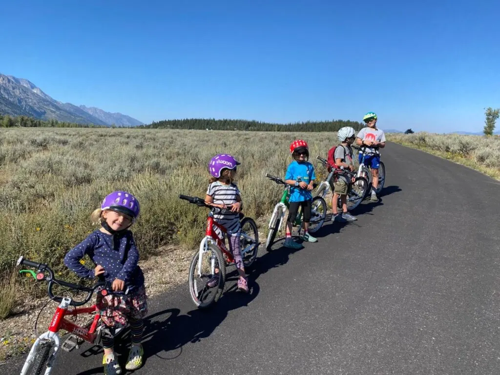 A group of kids riding various Woom bikes on a bike path together.
