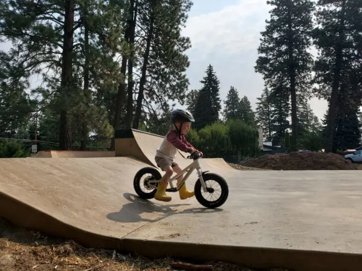 Little boy riding the dirt hero balance bike down a ramp at a skate park