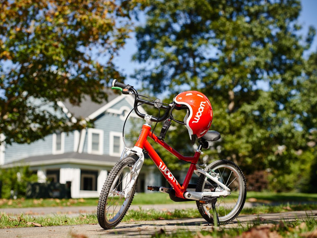 Red bike with red helmet, house and trees in a blurred background