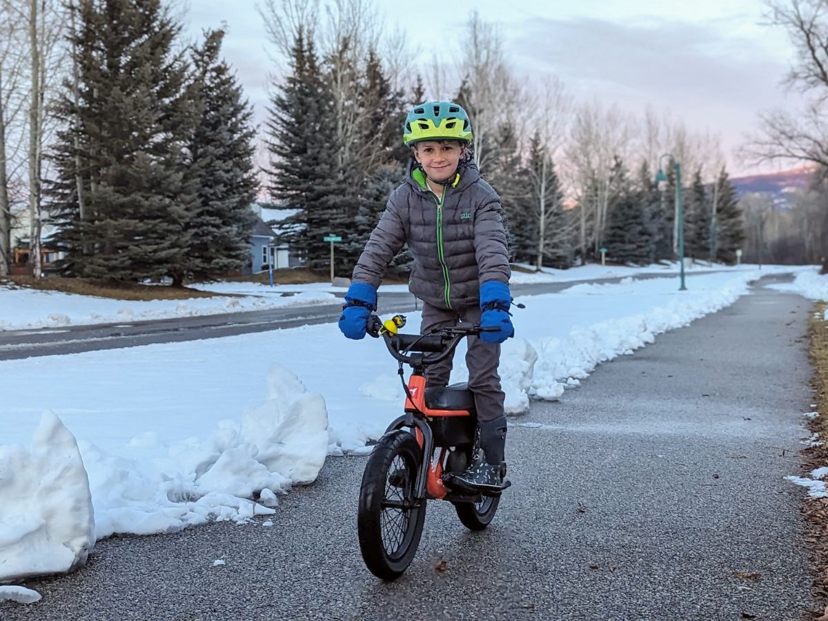 A boy rides an orange Himiway C1 Kids Electric Bike on a bike path.