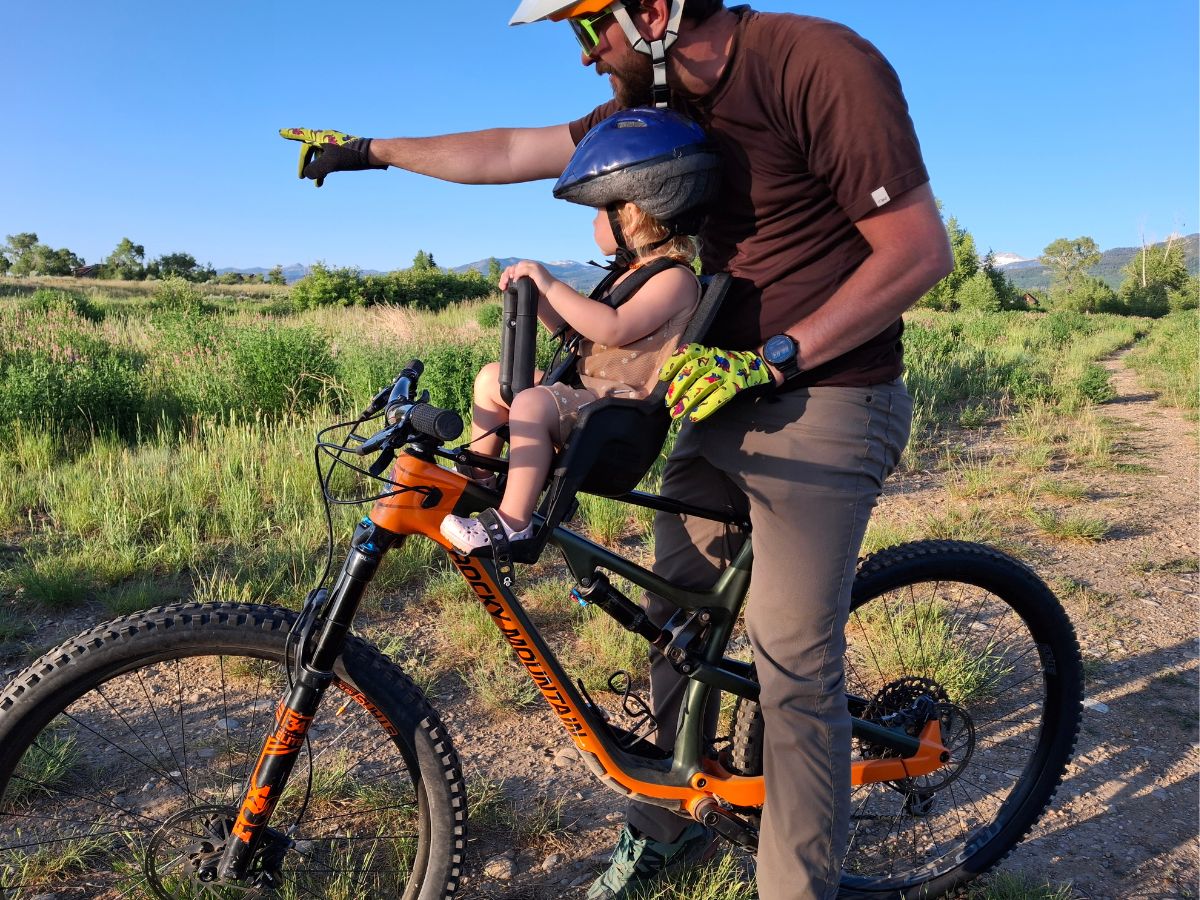 TMM and KRB Horizontal and Featured (30) A dad and baby sit on a mountain bike pointing at something in the distance.
